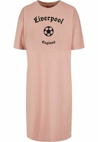 Lys rosa, kortermet kjole med ordet "Liverpool" og et fotballgrafikk, med "England" under i svart tekst. Glatt bomullsstoff.