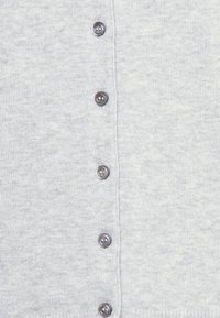 Šedý pletený cardigan s vertikálním řadou šesti tmavých knoflíků, hladkou texturou a jemným melírováním po celém povrchu.