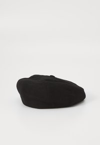 Black flat cap made of woven fabric, rounded shape with a small top button and soft texture, featuring subtle stitching details.