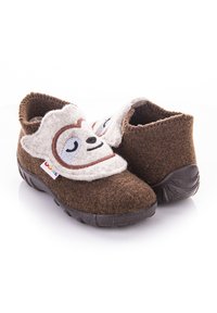 Brązowe filcowe kapcie z wzorem twarzy leniwca w kolorze kremowym. Owalny kształt z konstrukcją typu slip-on oraz teksturowaną czarną gumową podeszwą.