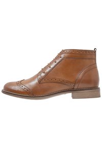 Brązowe skórzane botki za kostkę z detalami w stylu brogue, okrągłym noskiem i sznurowanym zapięciem. Posiadają niski, warstwowy obcas oraz kontrastowe przeszycia na podeszwie.