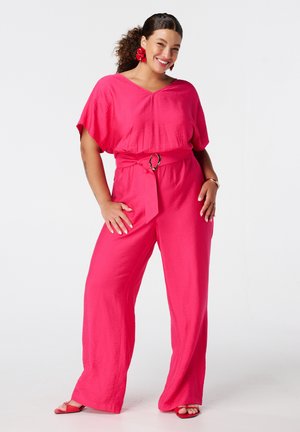 Combinaison fuchsia avec un décolleté en V, des manches larges et une ceinture avec un accent métallique. Tissu lisse et texturé ; design à jambes larges.