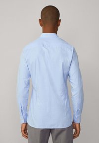 Lichtblauw button-up shirt met lange mouwen, voorzien van een textuurstof, achterpand naad, en standaard knopen op de manchetten.