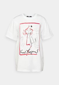 Bílý bavlněný tričko s grafickým designem a červenými akcenty, obsahující ná drawings oblečení, podepsaný Karlem Lagerfeldem. Krátké rukávy, kulatý výstřih.