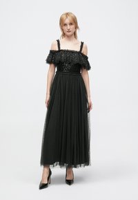 Robe noire décolletée avec un haut en dentelle froncée, un corsage pailleté et une jupe en tulle fluide, dotée d'une taille ajustée et d'une texture superposée.