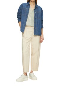 Denimhemd, lichtgroene gestreepte top, beige op maat gemaakte broek, en witte sneakers, allemaal met een ontspannen pasvorm en strakke lijnen.