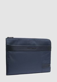 Custodia sottile per laptop blu navy con rifiniture in pelle nera e chiusura con cerniera, marchiata con il logo "Piquadro" sulla parte anteriore.