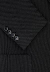 Czarna prążkowana tkanina o teksturowanej powierzchni. Posiada cztery czarne guziki na mankiecie oraz detal kieszeni widoczny na dole.