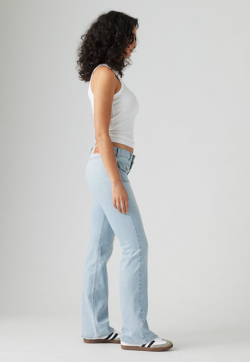 Jean évasé bleu clair en denim, avec un design classique à cinq poches, une taille mi-haute et des détails de couture contrastants.