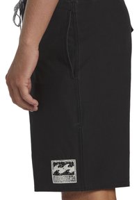 Zwarte boardshorts met een zijzak, gemaakt van een gestructureerde stof, met contrasterende stiksels en een wit logopatch op de onderste zoom.