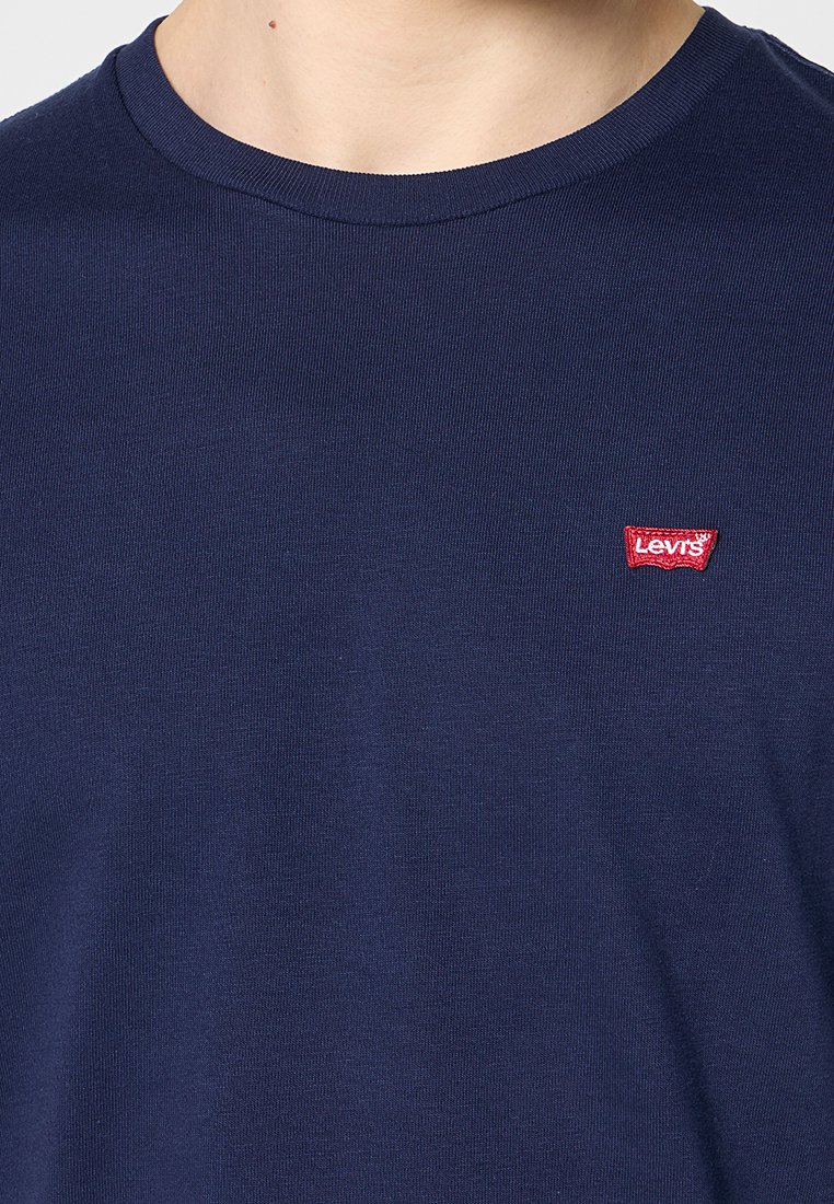 Camiseta de algodón de manga corta en azul marino con cuello redondo y un pequeño parche con el logo de Levi's en rojo en el lado izquierdo del pecho. Textura suave.