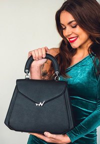 Schwarze Handtasche aus Kunstleder mit strukturiertem Design, silbernem Zubehör und einem markanten Logo. Verfügt über einen oberen Griff für praktisches Tragen.