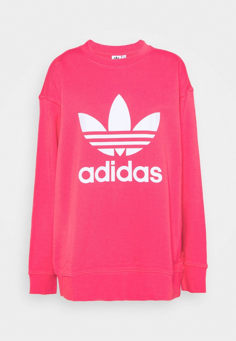 Sweatshirt rose avec manches longues, encolure ronde et un logo Adidas blanc comportant trois bandes au-dessus de trois formes ressemblant à des feuilles.