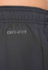 Mustat DRI-FIT-liikuntashortsit, joissa on joustava vyötärönauha ja sileä pinta. Sivussa on vaaleanharmaa hienovarainen logo.