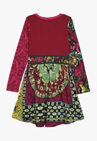 Sukienka z długim rękawem, z bordową górą, kolorową spódnicą z wzorami kwiatowymi i geometrycznymi oraz marszczonym detalem w talii.