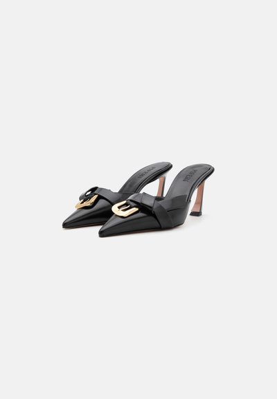 Tacchi slingback in pelle nera con punta affusolata, dettagli in hardware dorato e un piccolo tacco a spillo. Texture liscia e design minimalista.