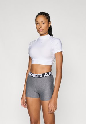 Witte crop top met korte mouwen en een hoge hals, gecombineerd met grijze sportieve shorts met een zwarte "UNDER ARMOUR" tailleband.