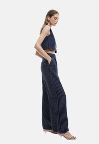 Ensemble deux pièces bleu marine à rayures, comprenant un crop top sans manches et un pantalon large, fabriqué en tissu léger.