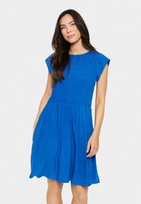 Blå klänning med kort ärm och tajt bodice, med rynkad textur och flödande kjol. Tillverkad av lättviktsmaterial, med len yta och medellång längd.