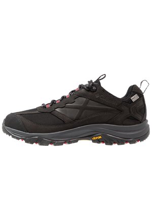 Chaussure de randonnée noire Columbia avec semelle grise, œillets rouges, adhérence Vibram et languette au talon, présentée de profil sur fond blanc.