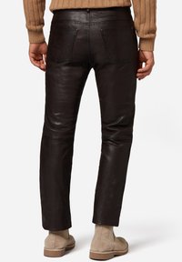 Sorte læderbukser med en glat tekstur, slim fit og syninger. Sammen med beige ruskinds ankelstøvler.