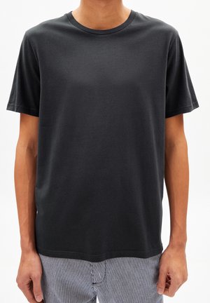 Czarny T-shirt z krótkim rękawem wykonany z miękkiej bawełnianej mieszanki, z klasycznym okrągłym dekoltem i luźnym krojem. Szczegółowe przeszycia na brzegach.