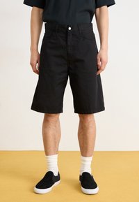 Black denim shorts with a straight cut, featuring front pockets and a button closure. Paired with black slip-on shoes and white socks.