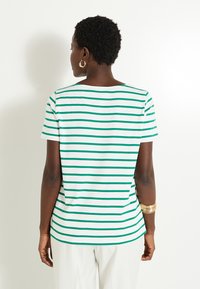 Camiseta de manga corta en blanca con rayas horizontales verdes. Cuello redondeado sencillo, material de algodón suave y un corte relajado.