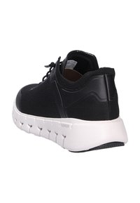 Zapatilla negra con suela blanca flexible, parte superior de malla, soporte trasero para el talón y cordones, en ángulo para mostrar detalles laterales y traseros.