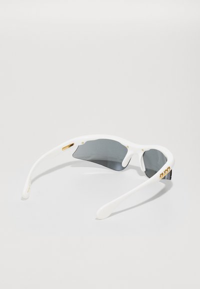 Occhiali da sole bianchi con lenti grigie. Presentano un design elegante, una leggera curvatura e dettagli in hardware dorato sulle aste.
