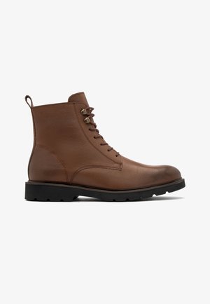 Brązowe skórzane botki na kostkę z tłoczoną powierzchnią, sznurowanym zapięciem i wytrzymałą czarną gumową podeszwą. Wyposażone w pętelkę do łatwego zakładania.