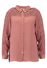 Růžová blůza s límečkem, se krajkovými panely na ramenou, dlouhými rukávy a stříbrnými knoflíky vpředu.