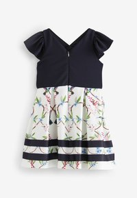 Námořnický top s volánovými rukávy a výstřihem do V, přecházející do sukně s květinovým vzorem na bílém pozadí, zelenými listy a námořnickými pruhovanými akcenty.