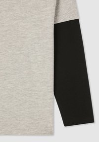 Camicia a maniche lunghe con corpo grigio chiaro e manica nera. Realizzata in tessuto morbido, presenta una texture liscia e un design semplice.