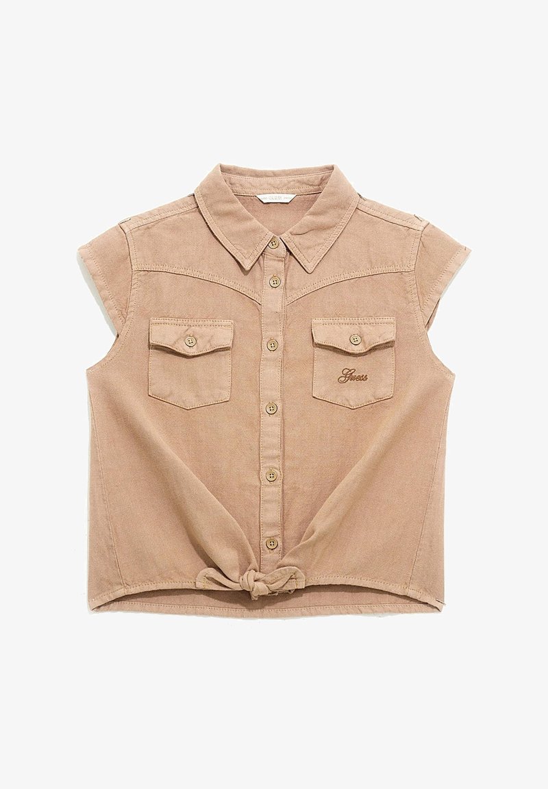 Lyhyhiihainen beige paita pehmeästä kankaasta, jossa on napillinen etuosa, kaksi rintataskua ja solmittu helmareunus. Paidassa on kaulus ja kirjailtu logo.