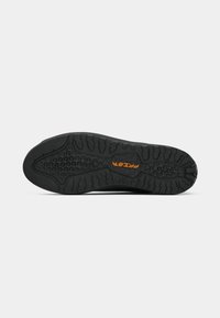 Sola de sapato preta com um padrão de aderência texturizado e um logótipo laranja. O design inclui relevos elevados para tração.