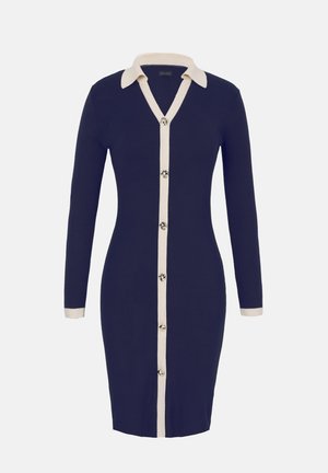 Sötétkék testhez simuló kötött ruha hosszú ujjakkal, fehér hegyes gallérral, fehér gombos elülső résszel és fehér mandzsettákkal.