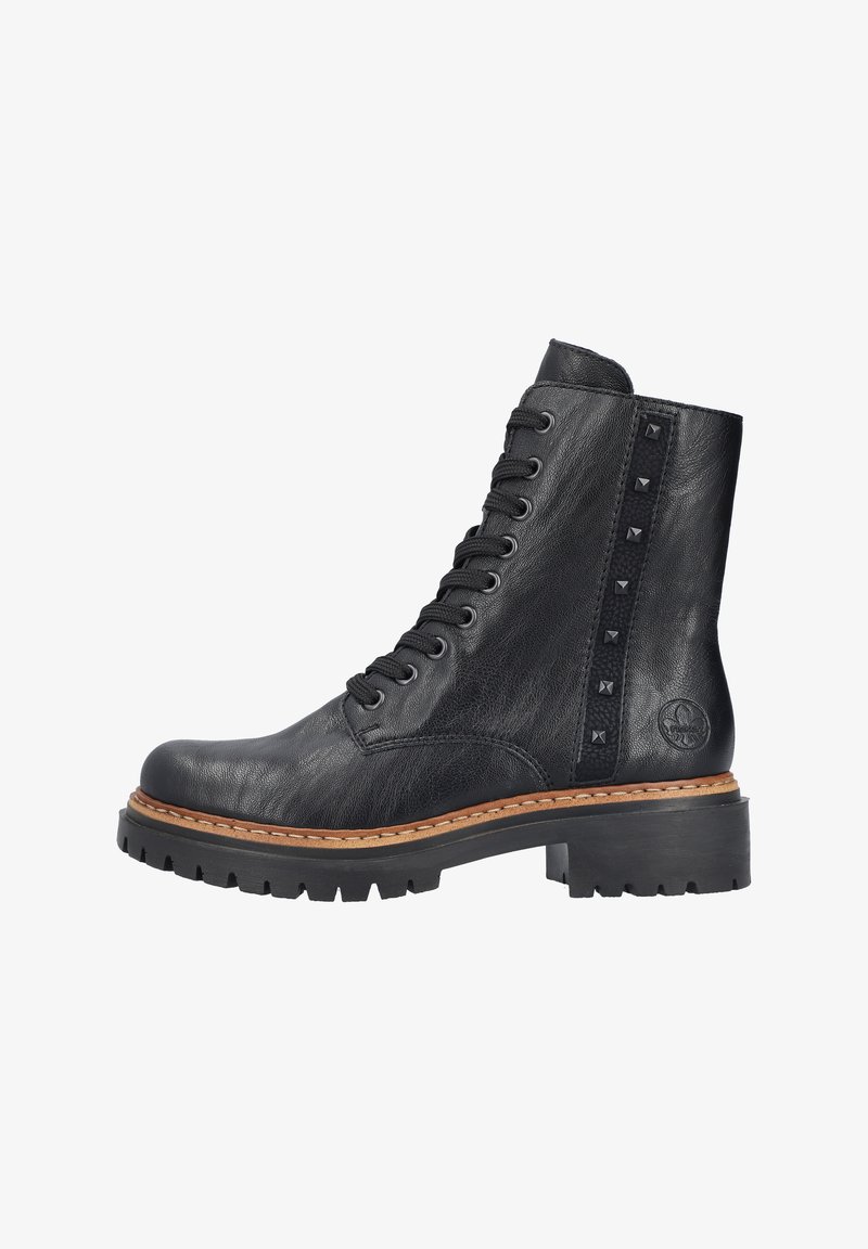 Bottine en cuir noir avec des lacets sur le devant, des clous le long du côté et une semelle en caoutchouc noir épaisse. Présente une semelle intermédiaire beige cousue.