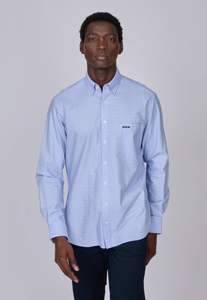 Chemise boutonnée bleu clair avec un petit motif à carreaux et un détail logo noir sur la poitrine. Manches longues et un design de col classique.