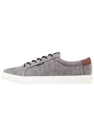 Basket basse décontractée avec tige en tissu gris, lacets noirs, semelle en caoutchouc blanche et accent en cuir marron au talon, vue de côté.