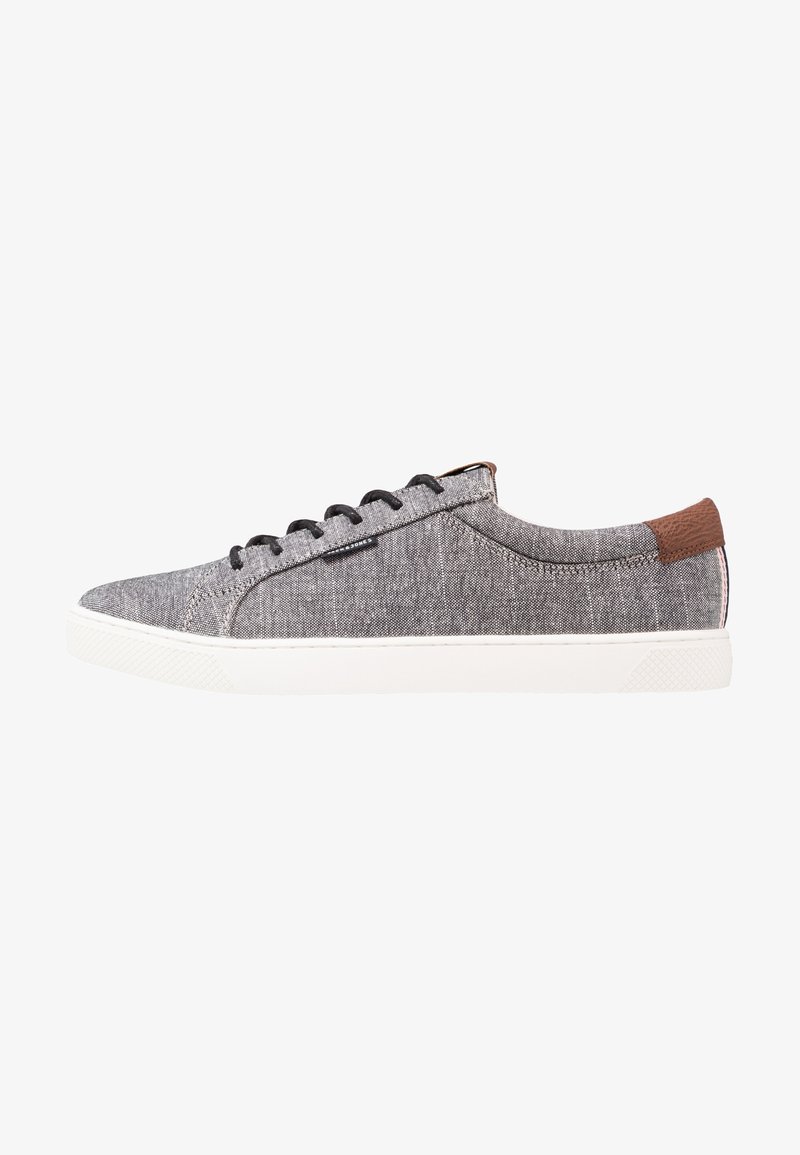 Basket basse décontractée avec tige en tissu gris, lacets noirs, semelle en caoutchouc blanche et accent en cuir marron au talon, vue de côté.