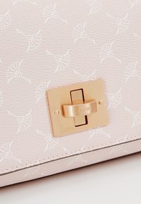 Borsa in pelle testurizzata di colore rosa chiaro con un motivo bianco e una chiusura rettangolare dorata con il nome del marchio inciso.