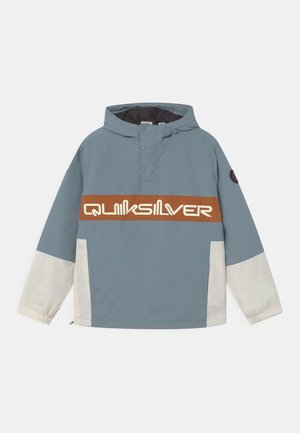 Veste à capuche bleue et blanche avec une bande horizontale marron sur la poitrine comportant le texte blanc du logo Quiksilver.