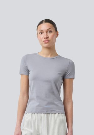 Graues T-Shirt mit kurzen Ärmeln aus weichem Stoff, Rundhalsausschnitt und figurbetonter Passform, getragen mit gestreiften hellen Hosen.