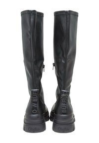 Paire de bottes hautes en cuir noir avec semelles épaisses et languettes à l'arrière étiquetées "Buffalo,", vues de dos sur fond blanc.