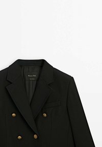 Musta kaksirivinen bleiseri sileästä kankaasta, jossa on kultaisen sävyn napit, lovetut kaulukset ja yksi rintatasku. Vuoritettu sisäosa.