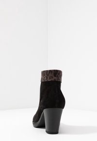 Stivale alla caviglia in suede nero con una fodera in stampa leopardata, tacco alto e suola in gomma testurizzata. Presenta una finitura liscia e una silhouette aderente.