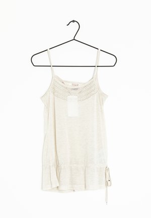 Beige mouwloze top met kanten halslijn, verstelbare zijstrik en dunne bandjes, hangend aan een zwarte hanger tegen een witte achtergrond.