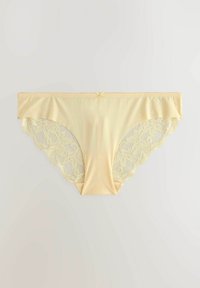 Panties gialli chiari con un frontale liscio, caratterizzati da accenti in pizzo floreale sui lati e un bordo ondulato. Dettaglio in piccolo fiocco alla vita.