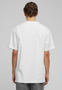 Hvid bomulds t-shirt med korte ærmer, rund halsudskæring og en afslappet pasform. Glat tekstur uden synlige mønstre eller detaljer.
